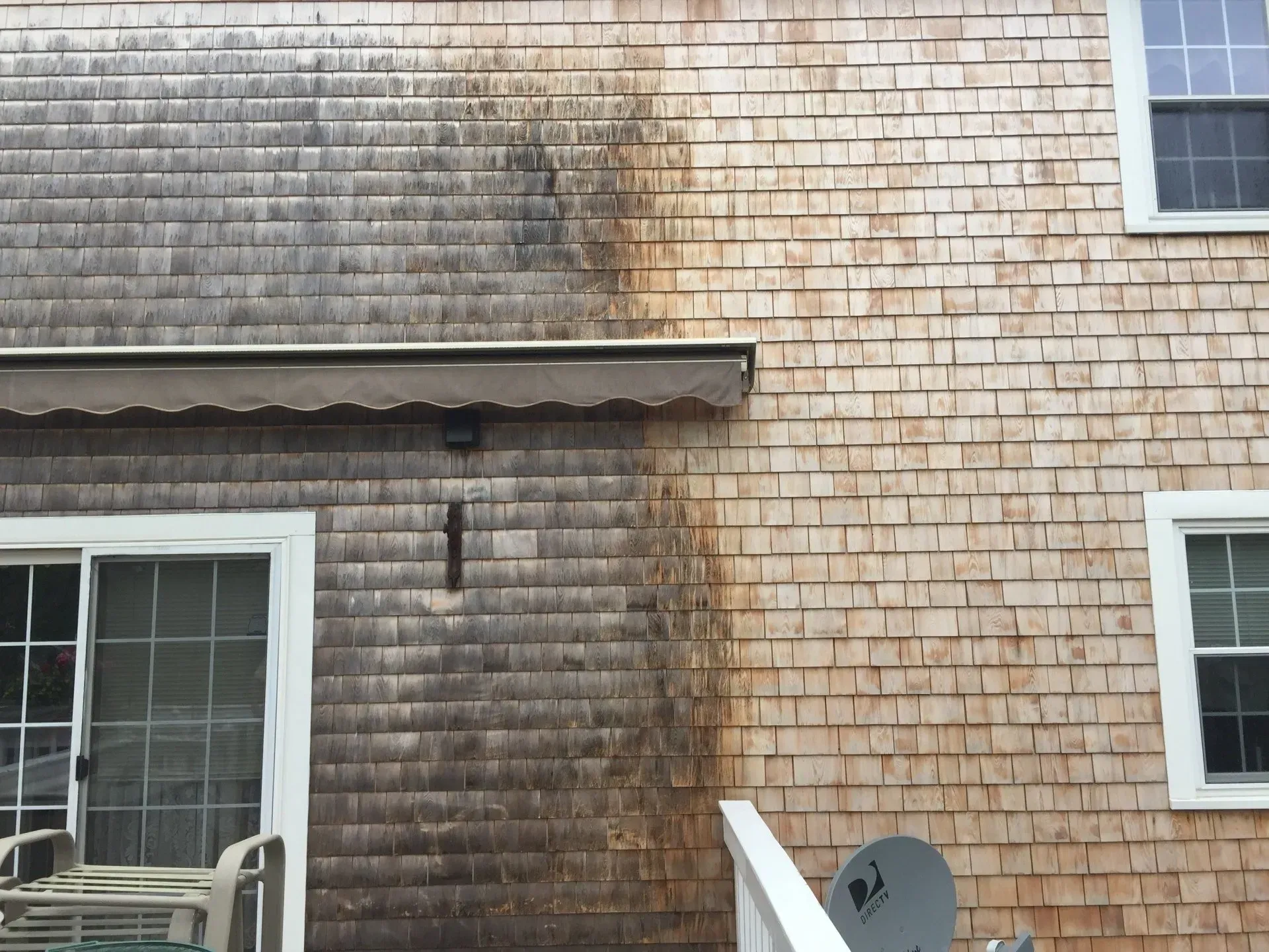 Exterior of a house with cedar shingle siding. One side is discolored, the other is clean.