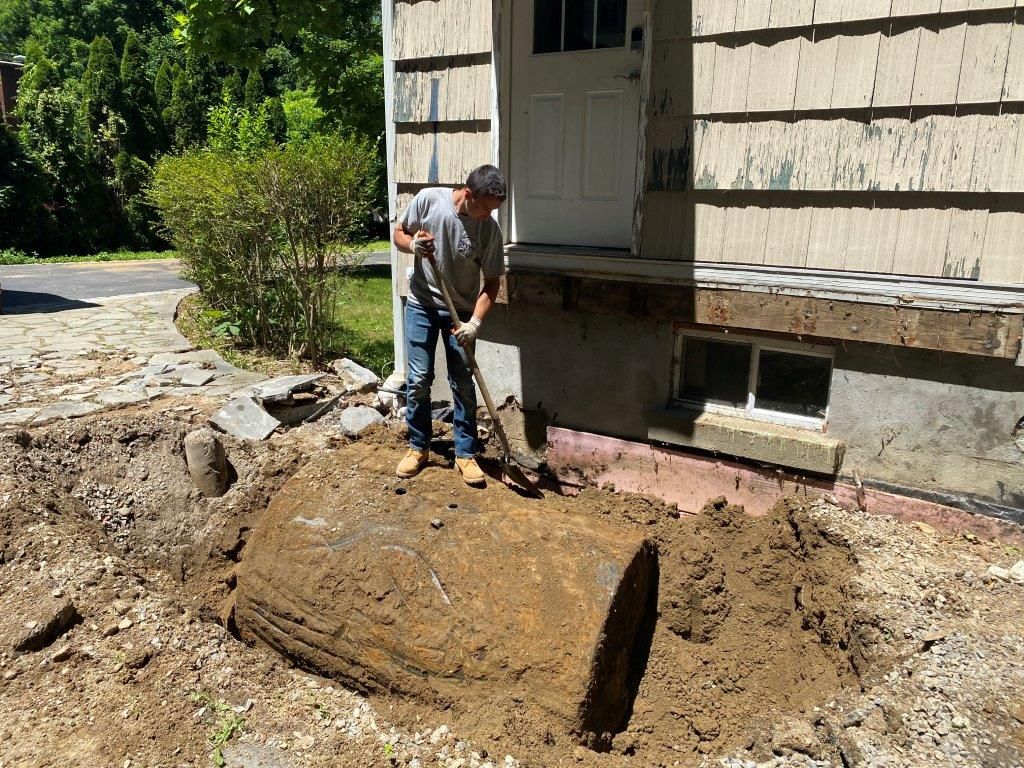 A man is digging a hole in the dirt in front of a house.