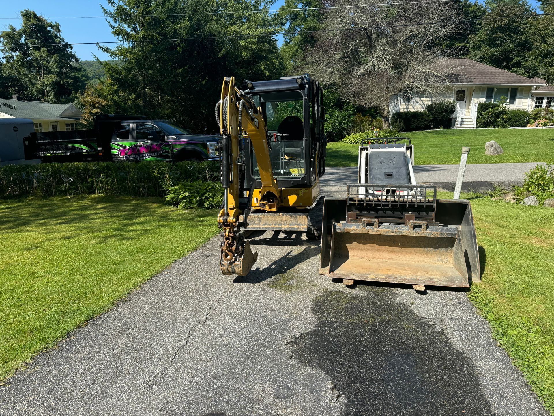 A small excavator is parked on the side of a gravel driveway