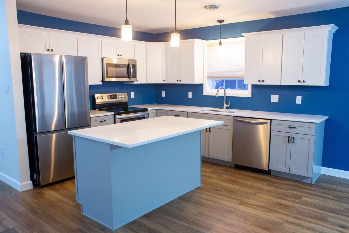 Modern kitchen with white cabinets, stainless steel appliances, blue walls, and a light blue island.