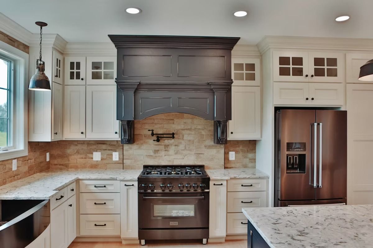 Kitchen with white cabinets, dark range hood, stainless steel appliances, and granite countertops.