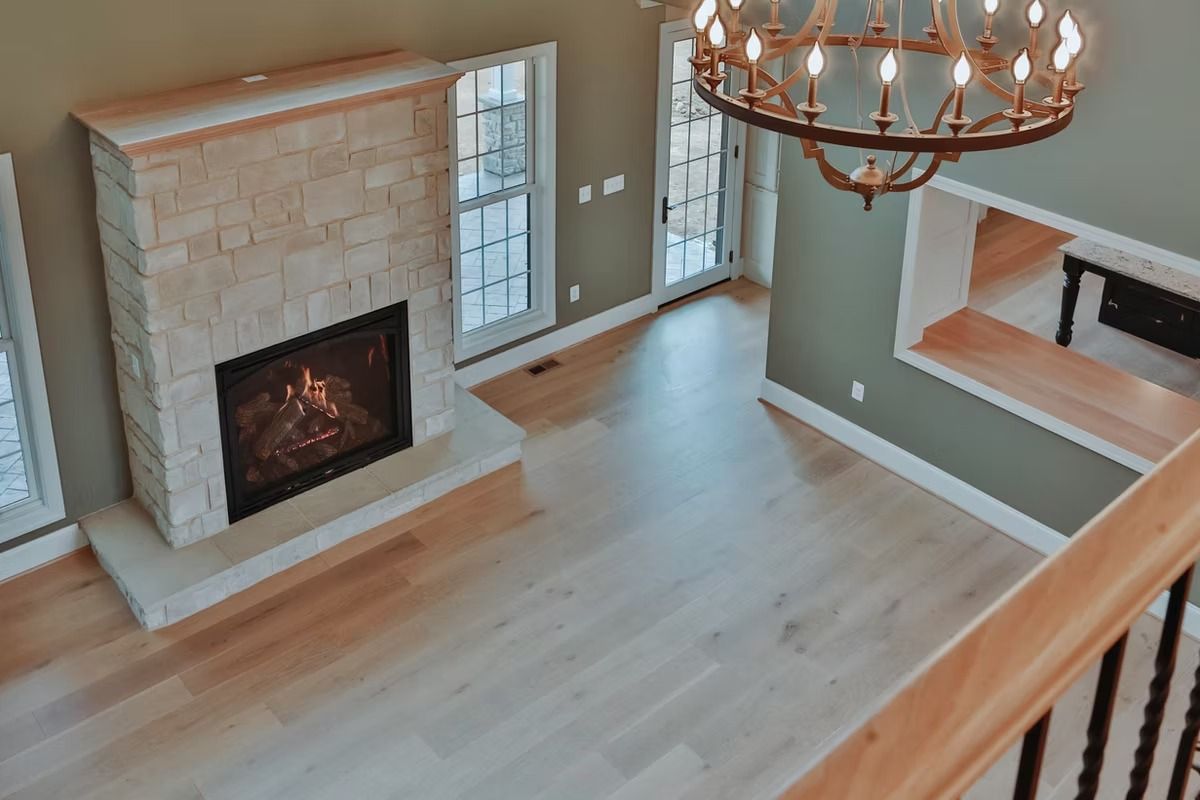 Overhead view of a living room with a fireplace, hardwood floors, and a chandelier.