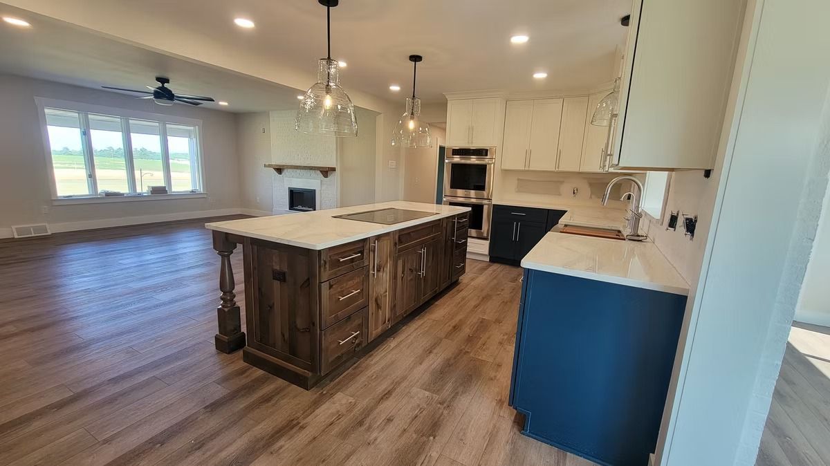 Kitchen with wooden island, white cabinets, and blue accent cabinets. Open to a living room with a fireplace.