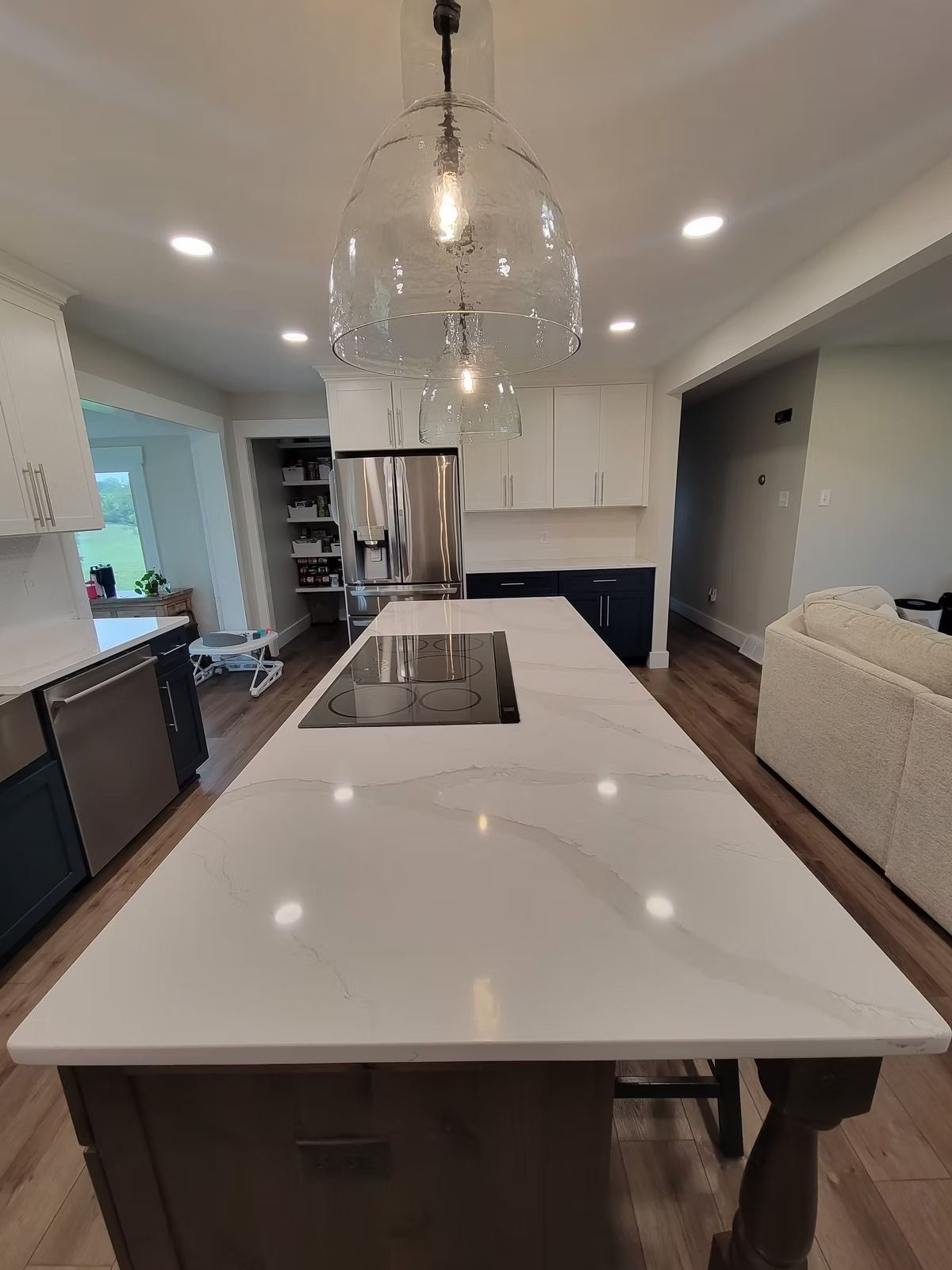 Modern kitchen with a long white countertop island and pendant lights.