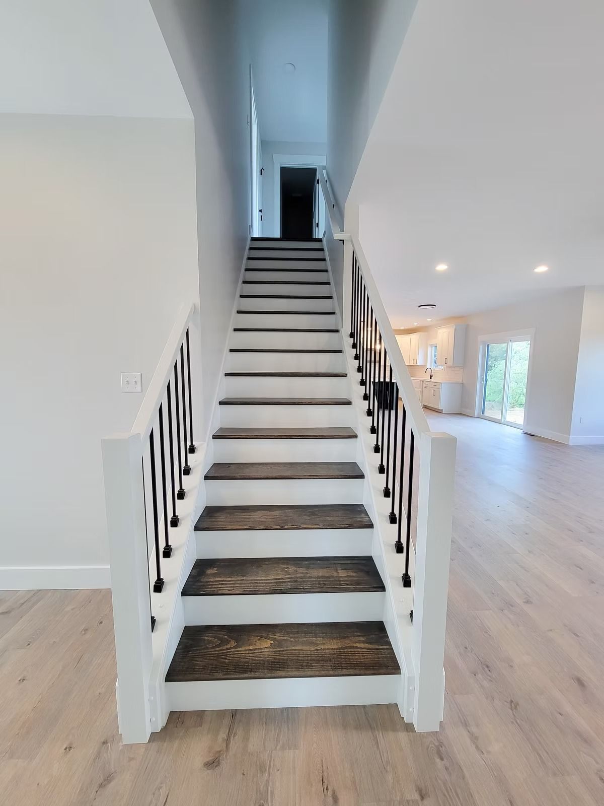 Wooden staircase with dark brown treads and white risers, black spindles and white banisters.
