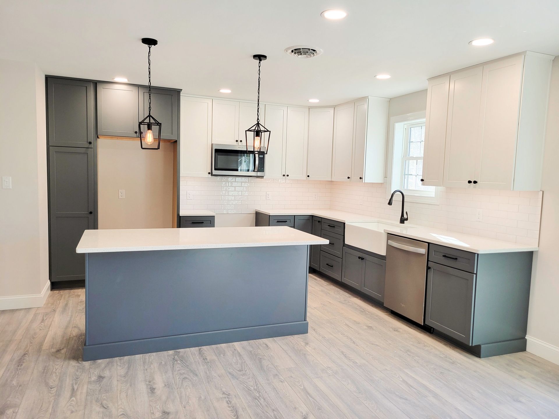 Modern kitchen with white and gray cabinets, island, and countertops; pendant lights.