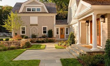 A large house with a large porch and a concrete walkway leading to it