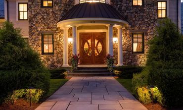 The front of a large stone house is lit up at night.