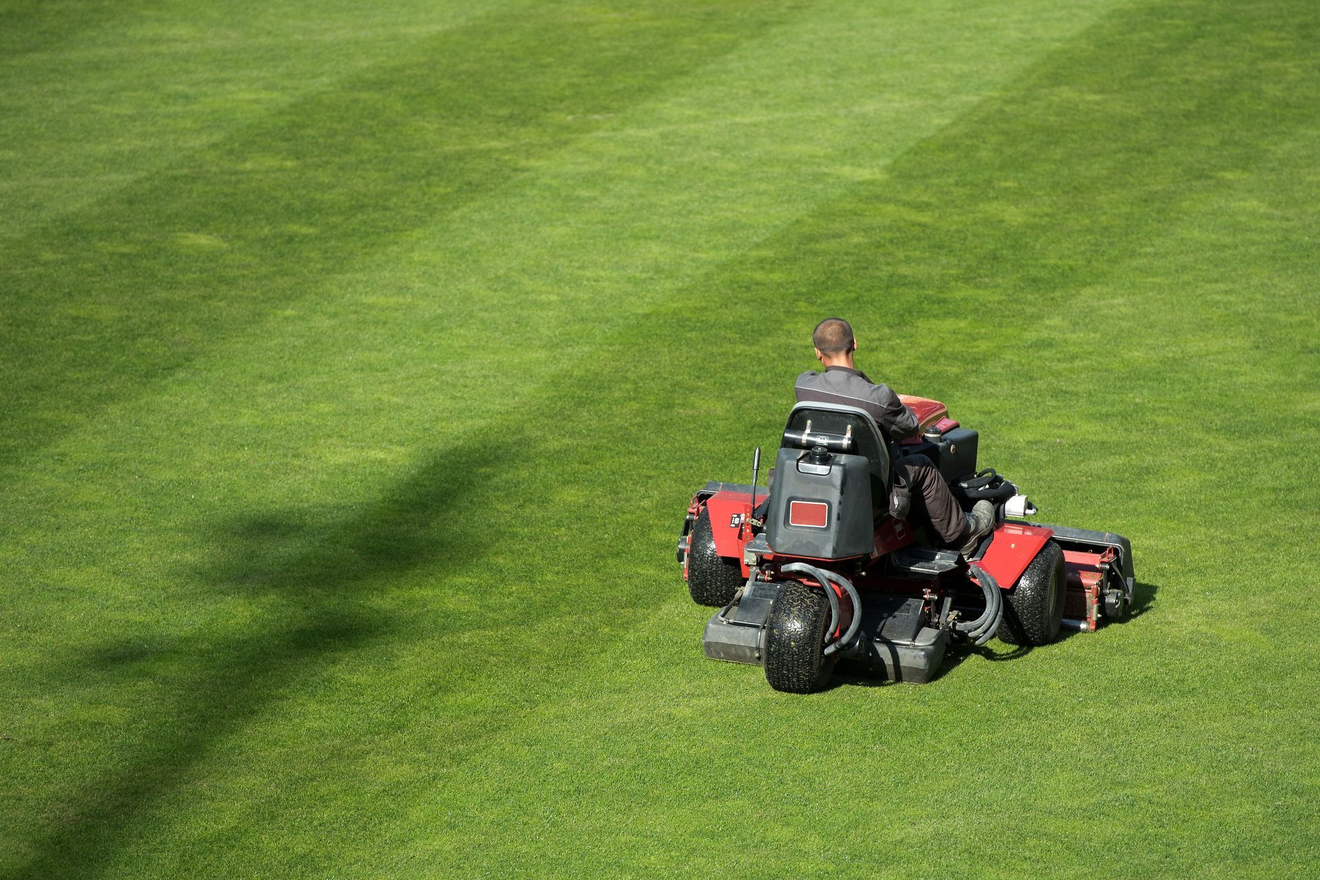 A man is riding a lawn mower on a lush green field.