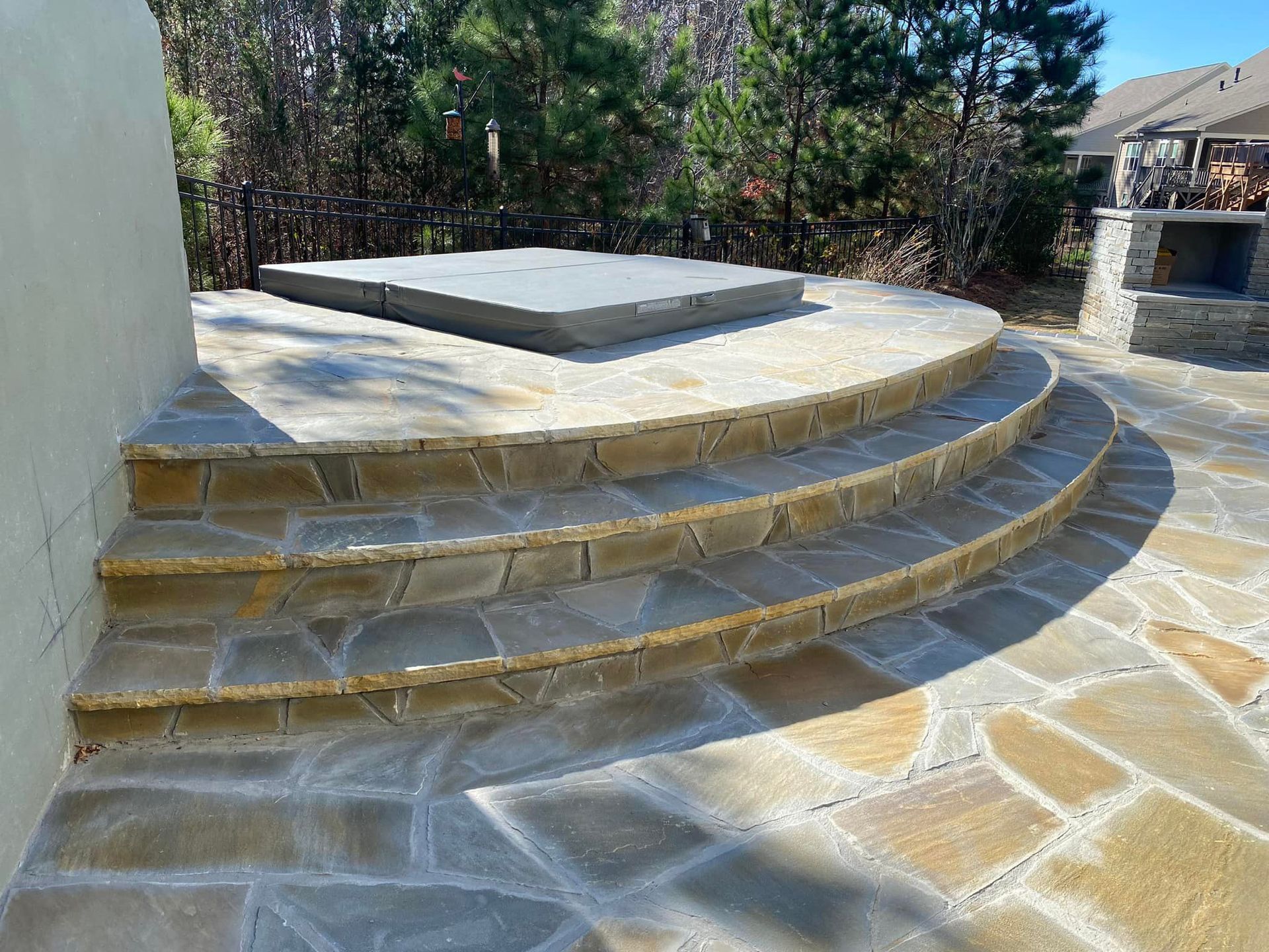A stone patio with steps leading up to a hot tub.