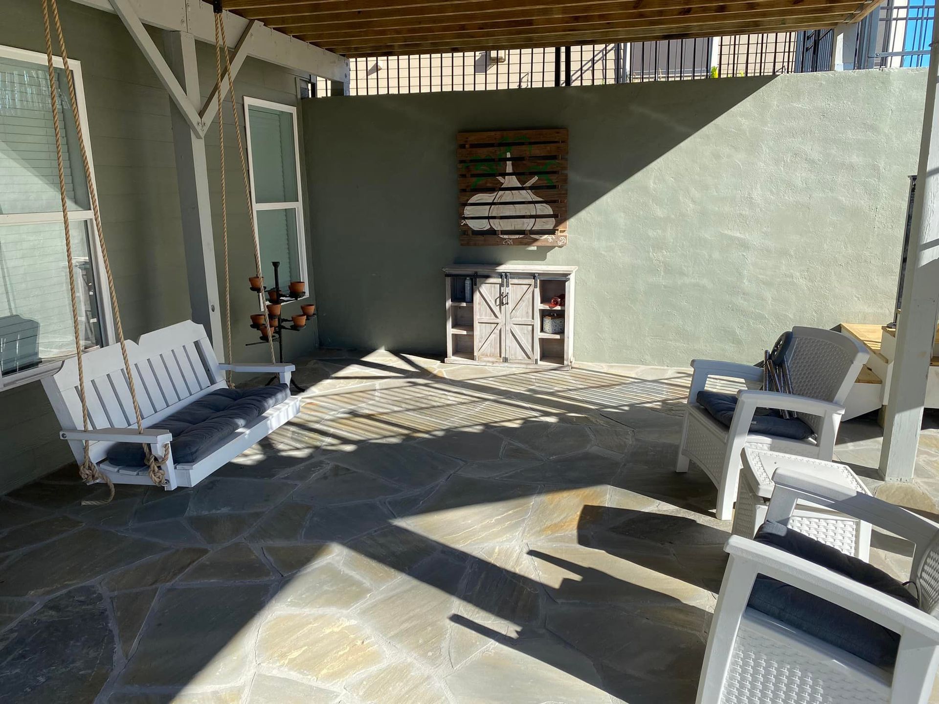 A patio with a swing and chairs under a canopy
