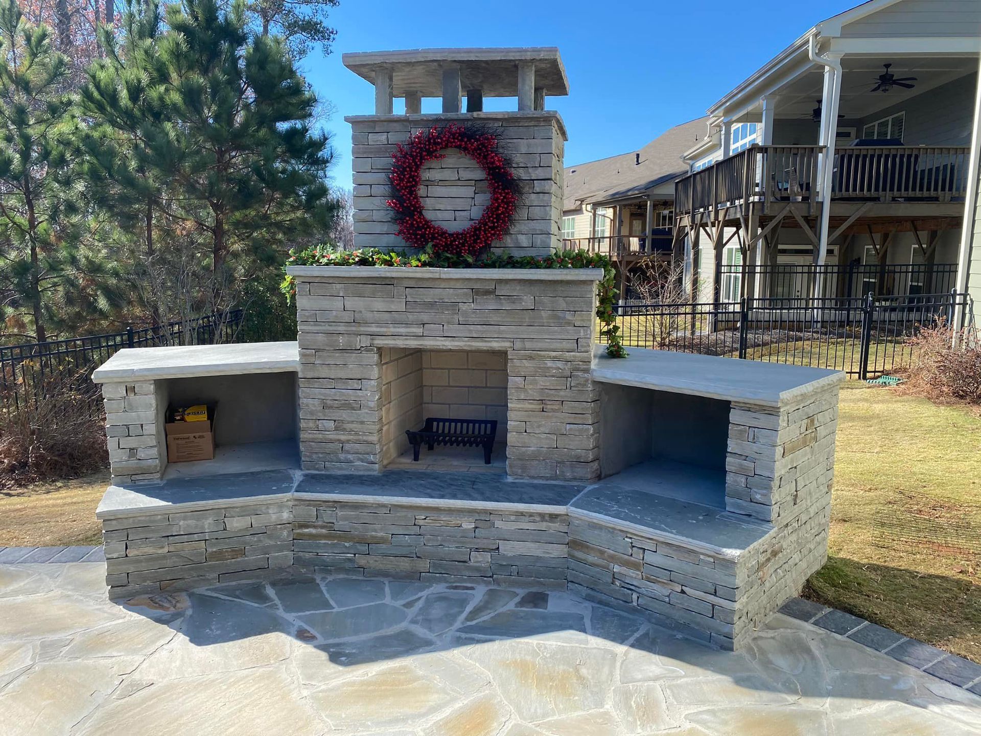 A brick fireplace with a wreath on top of it in a backyard.