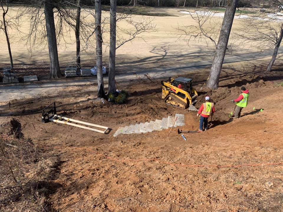 A group of construction workers are working on a hill with a bulldozer.