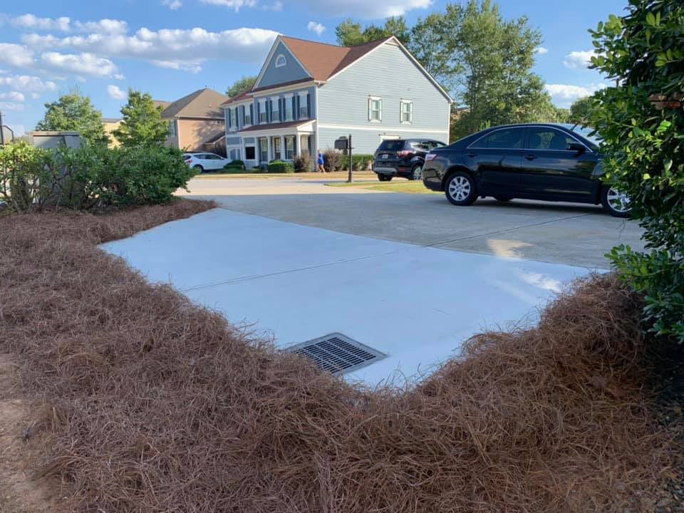 A black car is parked in a driveway in front of a house.