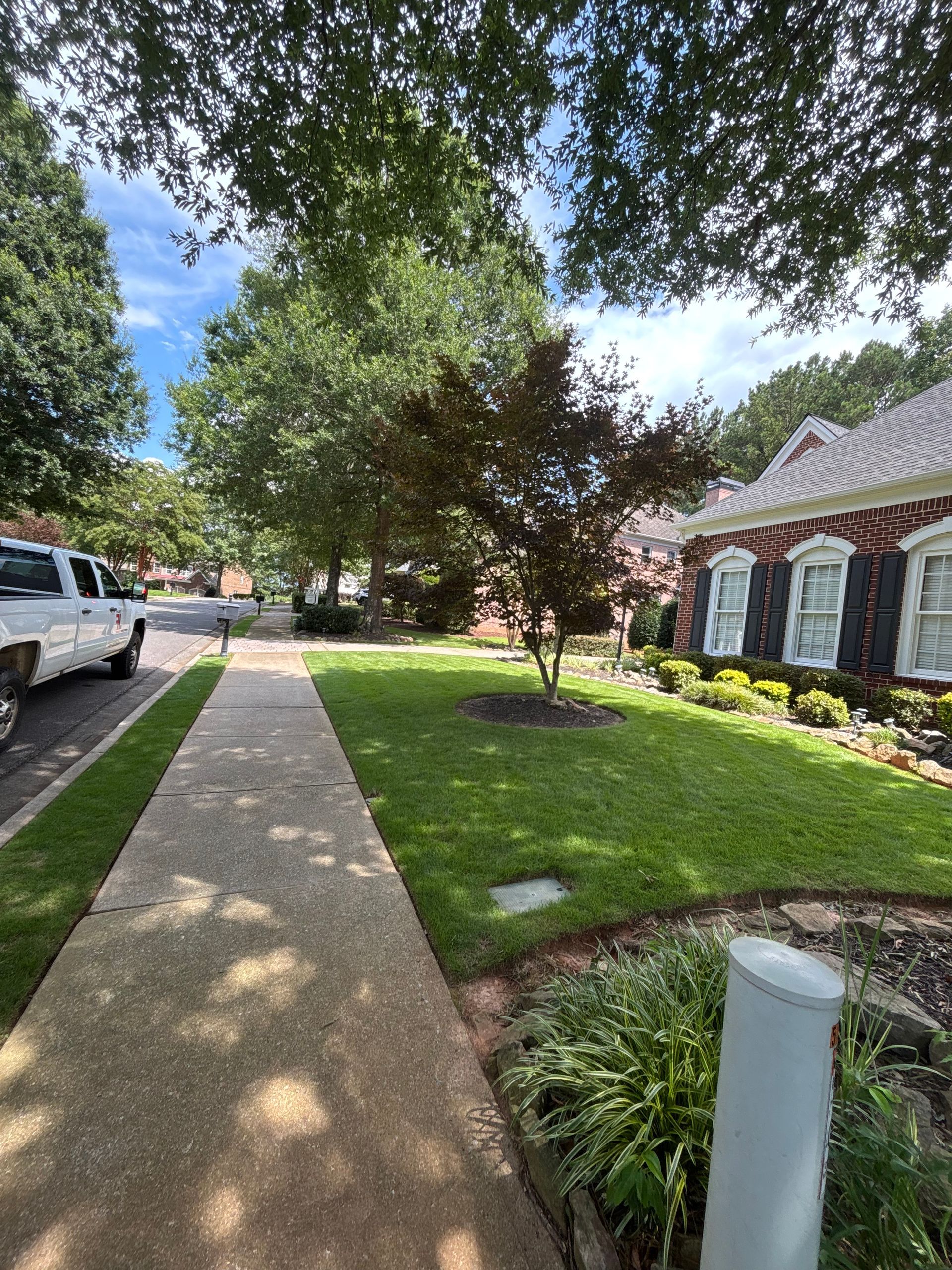A white truck is parked in front of a brick house.