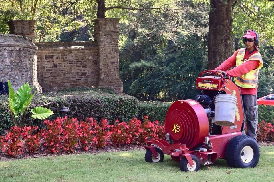 A man is riding a red lawn mower in a garden.