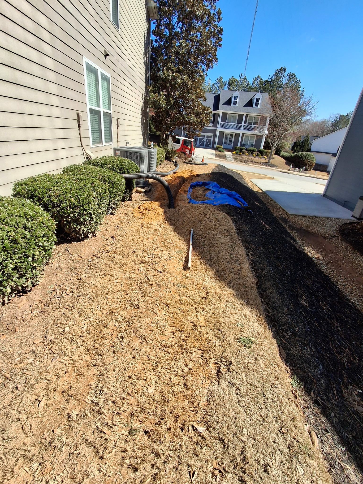 A large pile of mulch is sitting in front of a house.