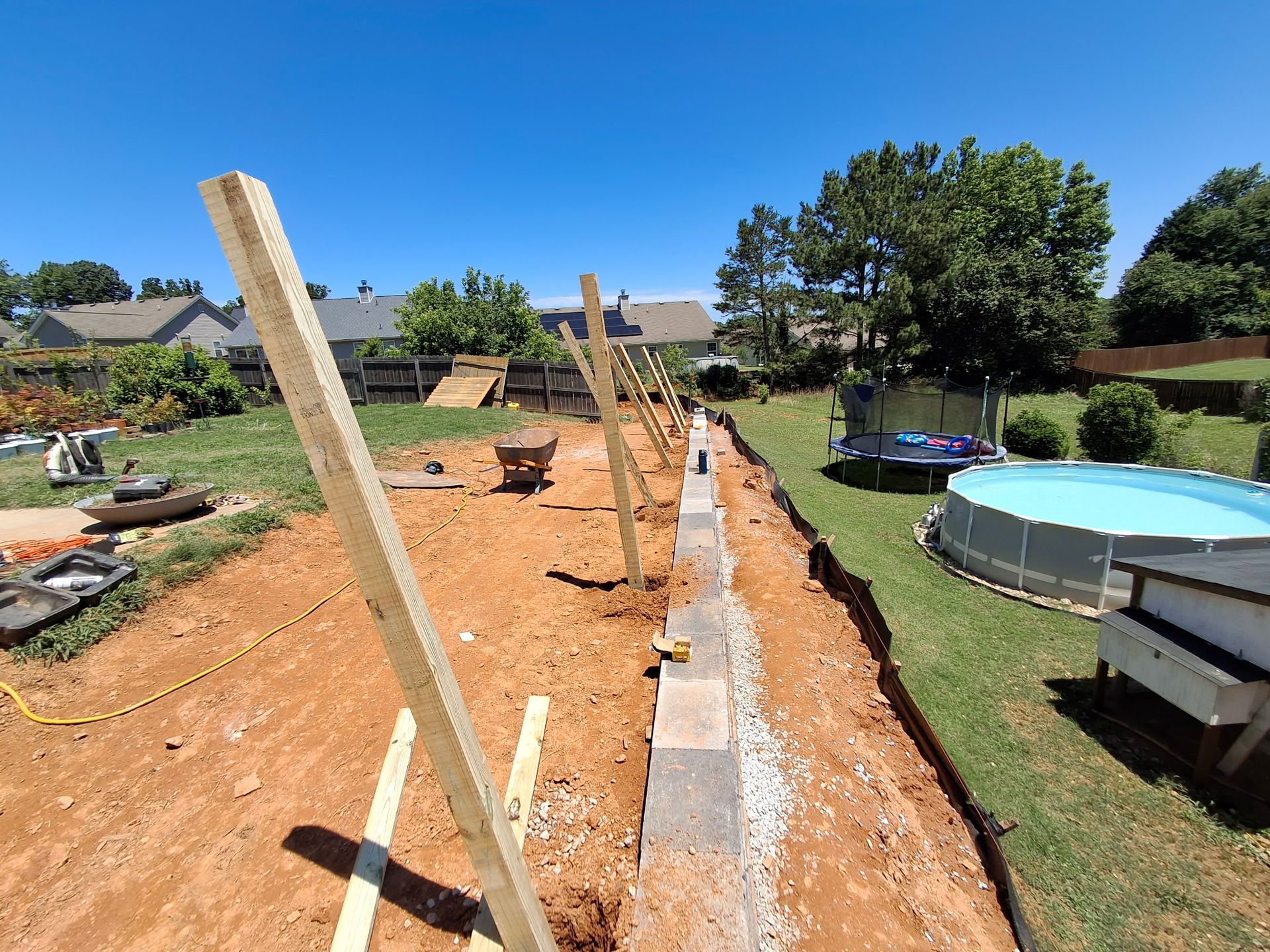 A fence is being built in a backyard next to a pool.