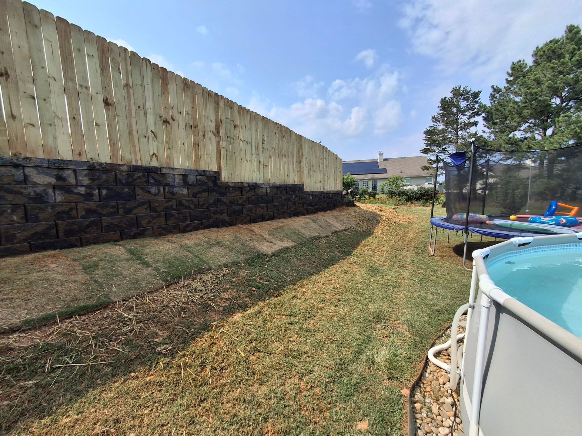 There is a pool in the backyard next to a wooden fence.