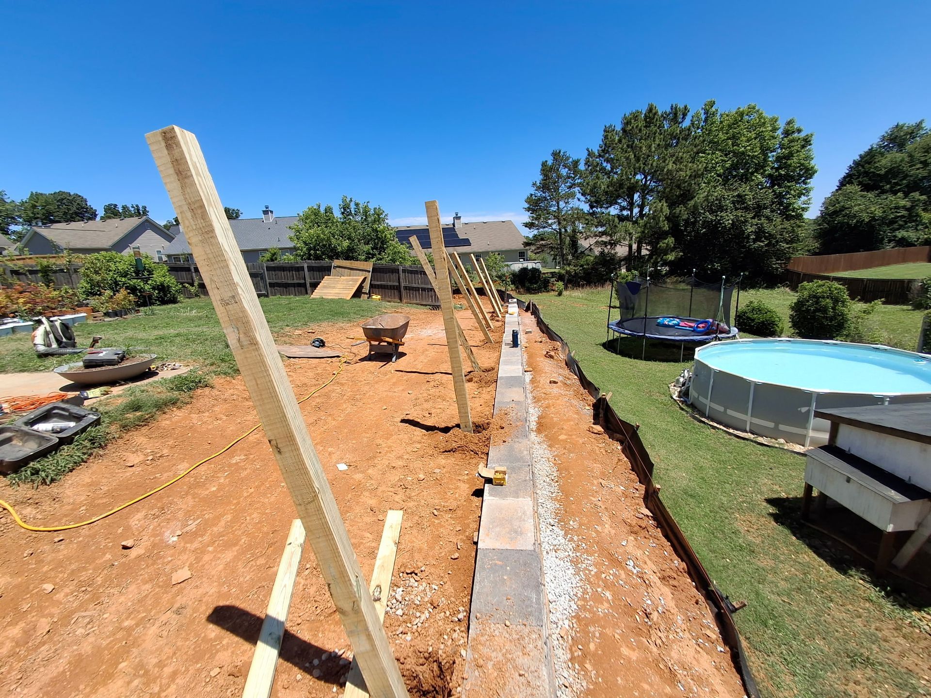 A fence is being built in a backyard next to a pool.