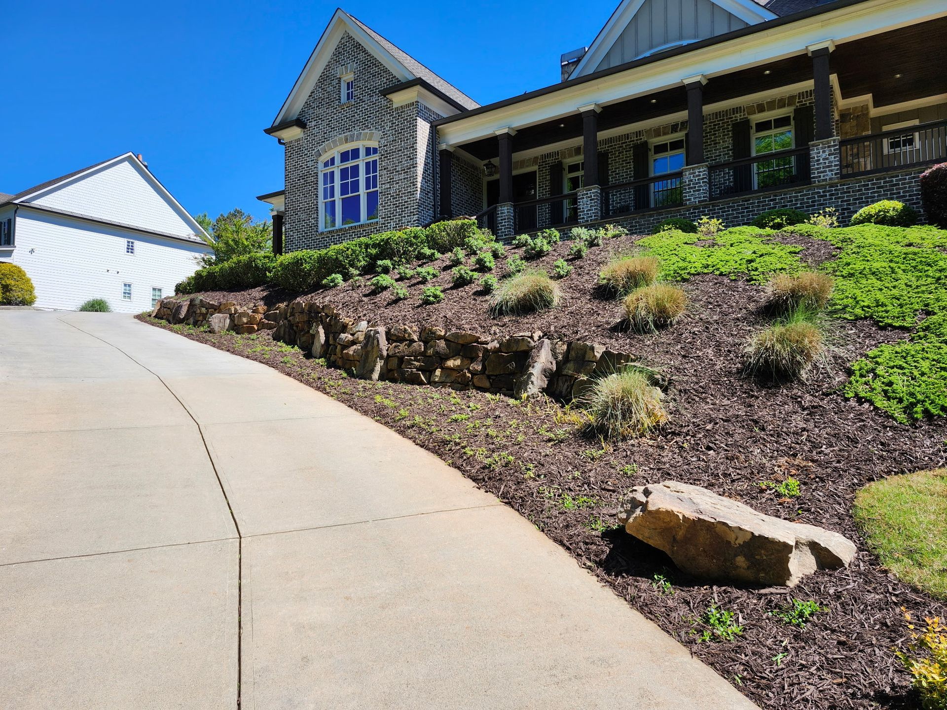 A large house is sitting on top of a hill next to a driveway.