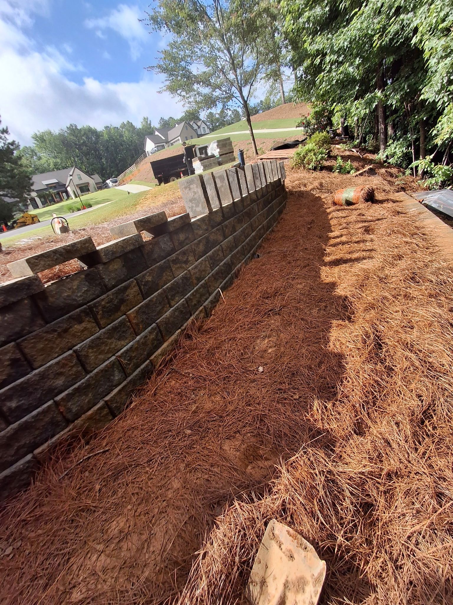A brick wall is being built in the middle of a dirt field.