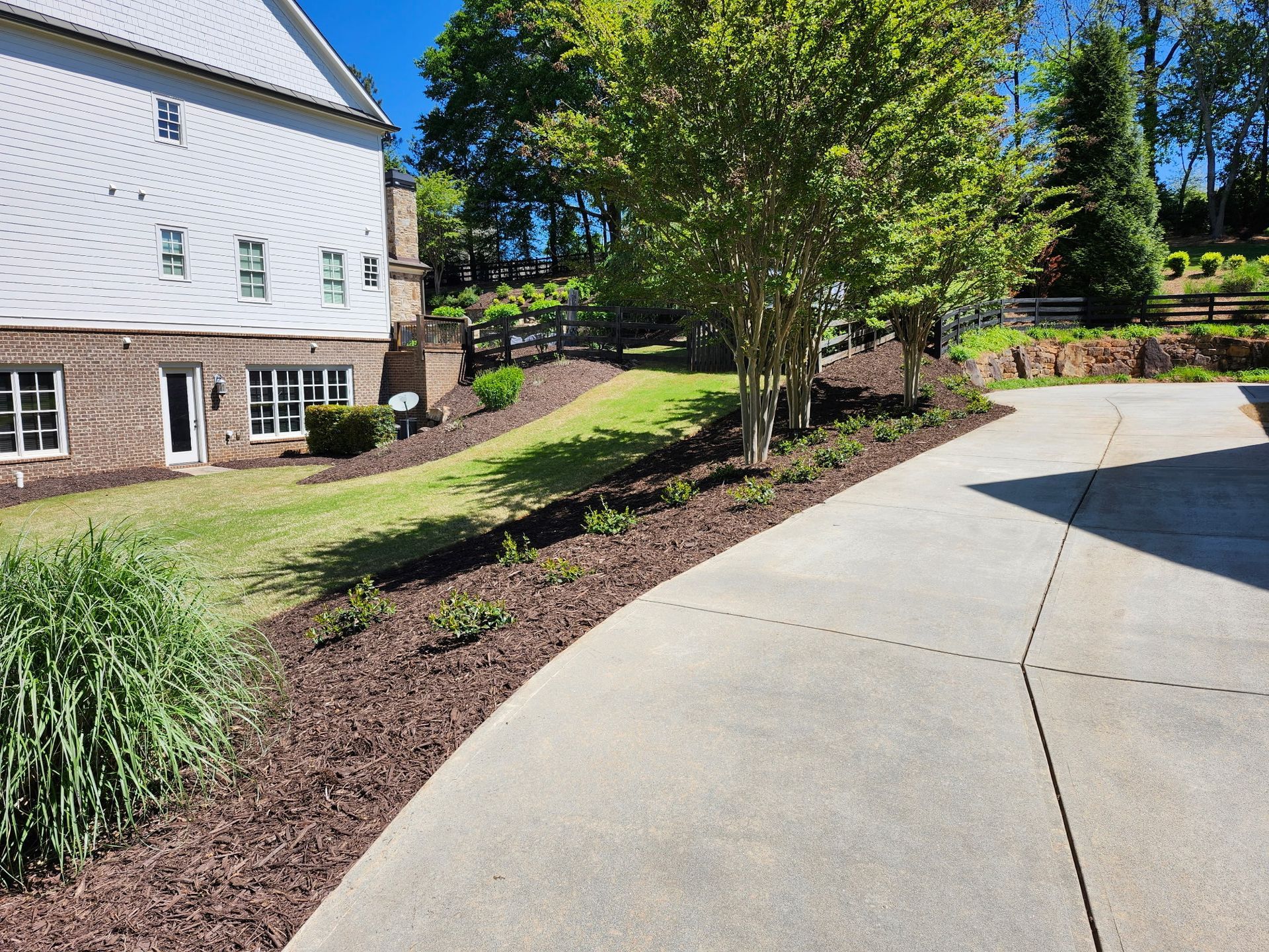 A white barn is behind a concrete driveway leading to it.