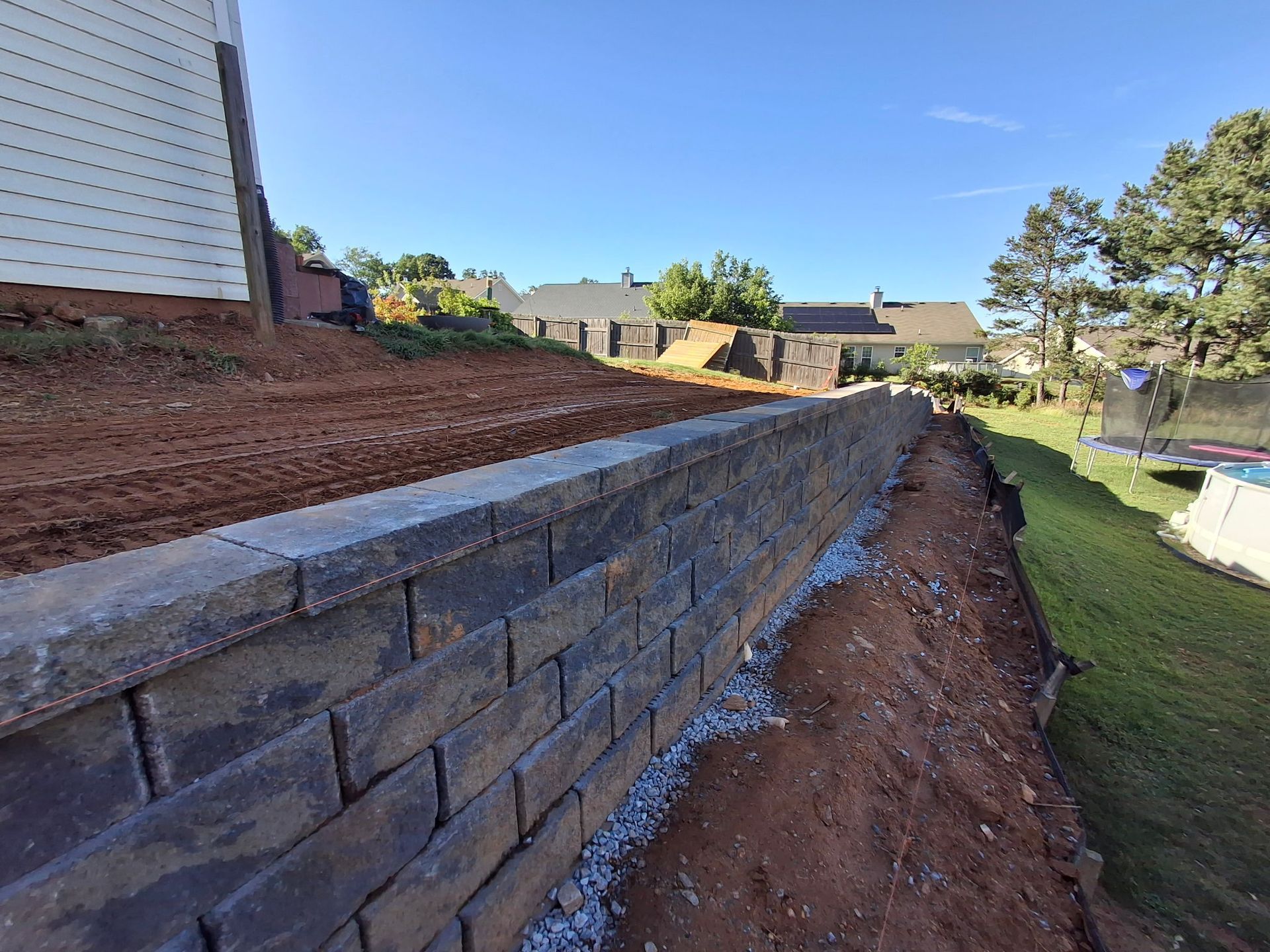 A brick wall is being built in the backyard of a house.