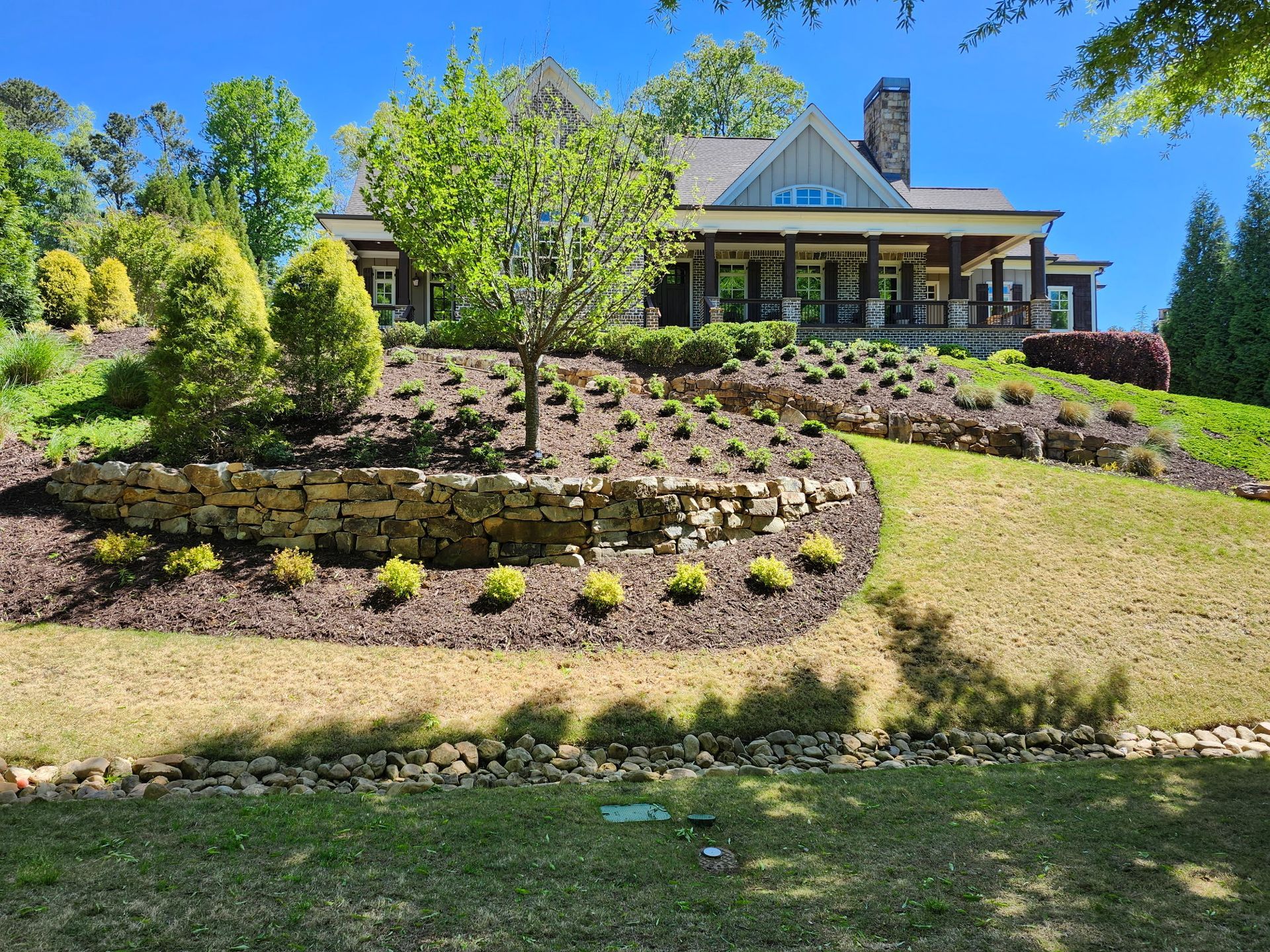 A large house is sitting on top of a hill surrounded by trees and bushes.