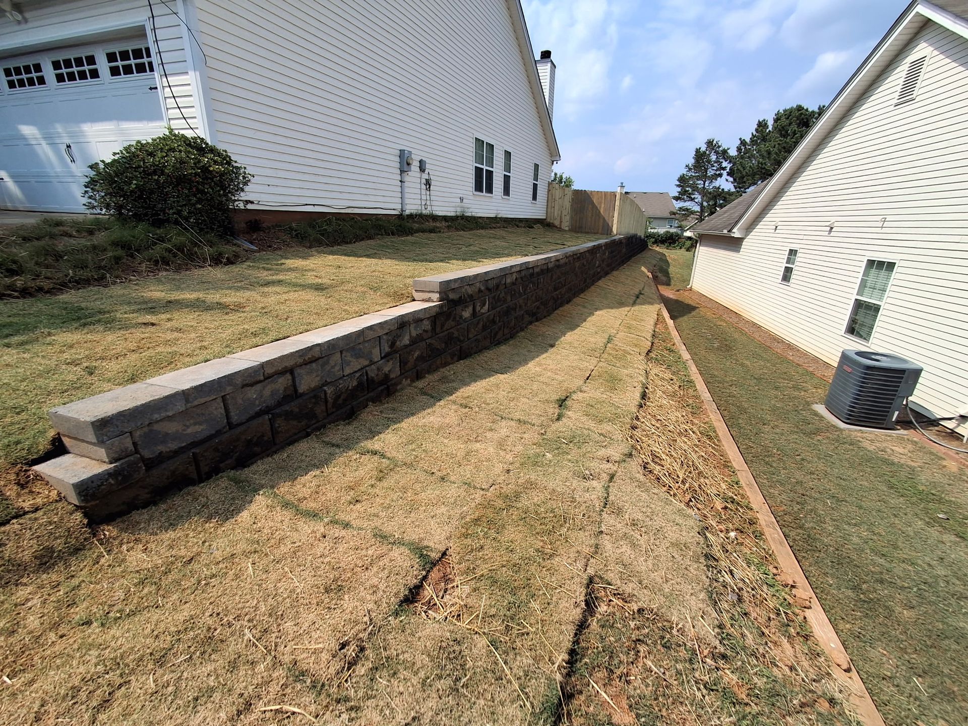 A brick wall is being built in the backyard of a house.