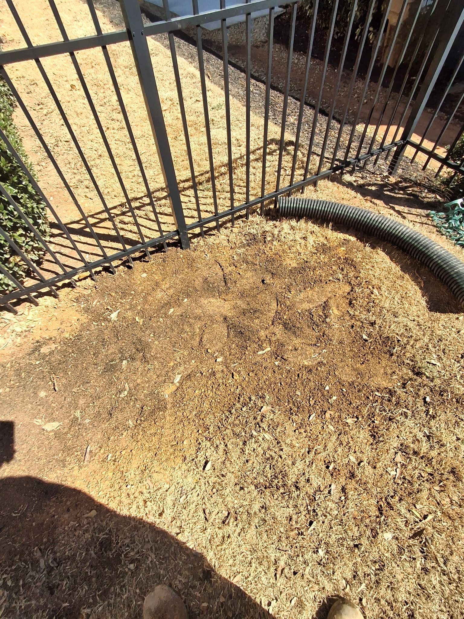 A vacuum cleaner is sitting on top of a pile of dirt next to a fence.