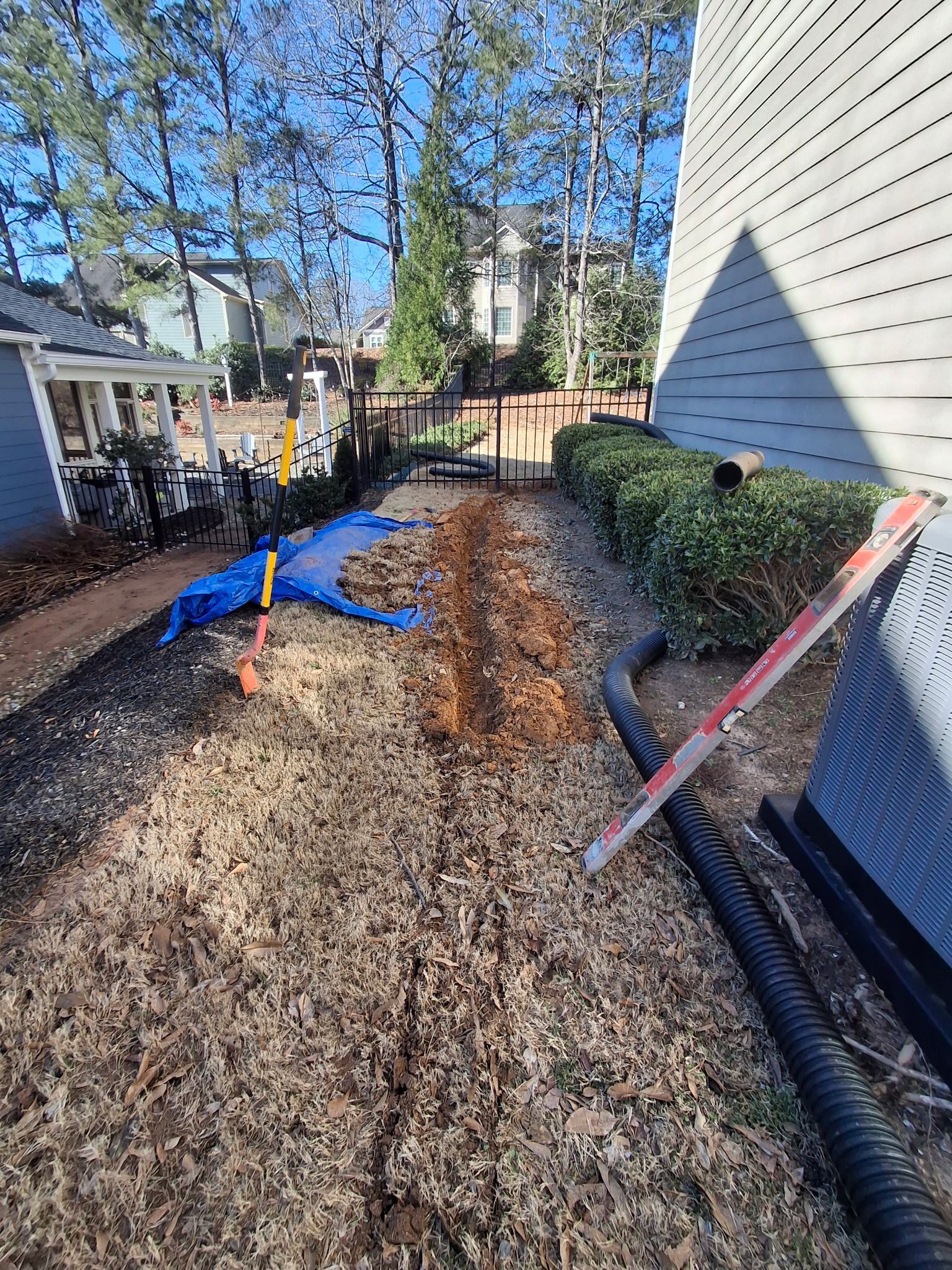A person is digging a hole in the ground in front of a house.