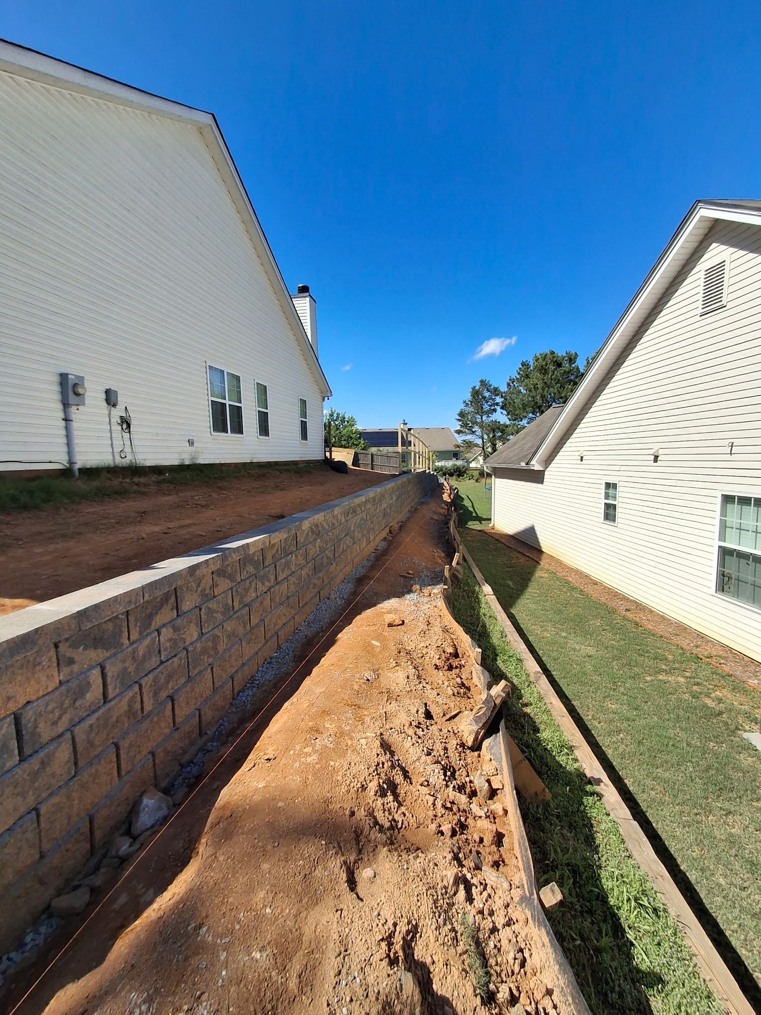 A brick wall is being built between two houses.