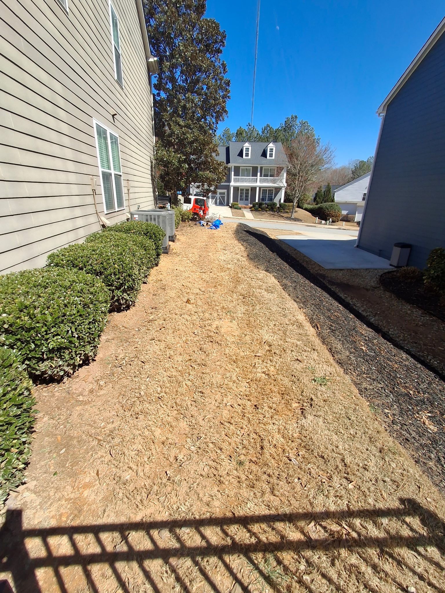 A path leading to a house with a lot of wood chips on the ground.