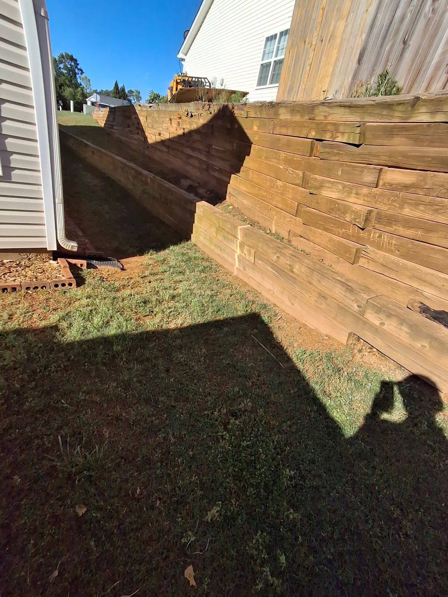 A shadow of a person is cast on a wooden fence next to a house.