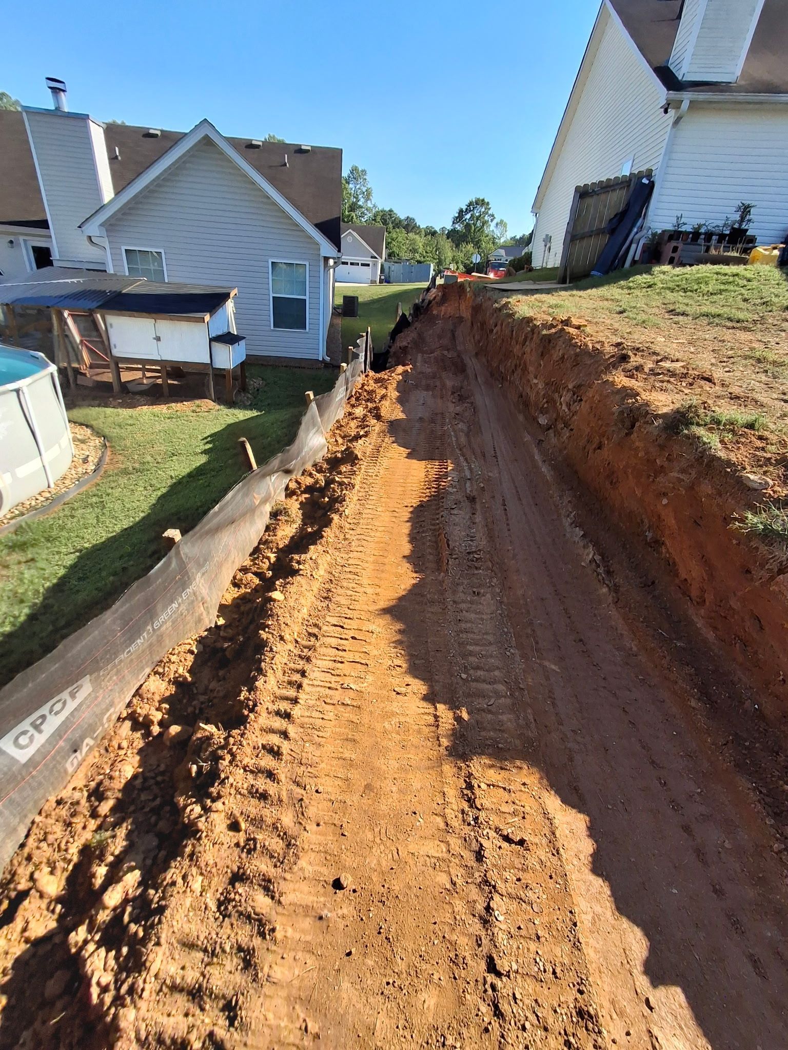 A dirt road leading to a house in a residential area.