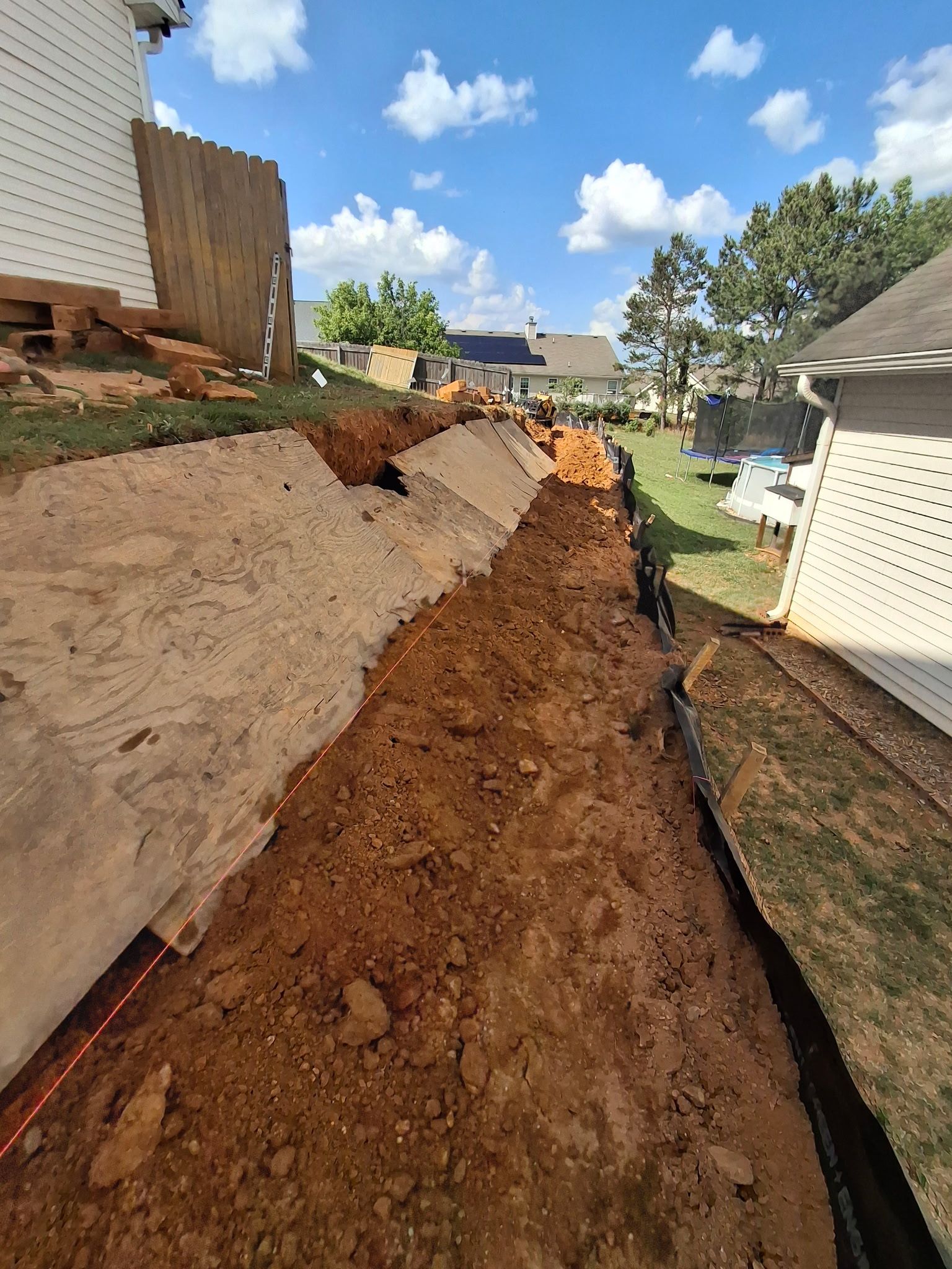 A drainage system is being installed in the backyard of a house.