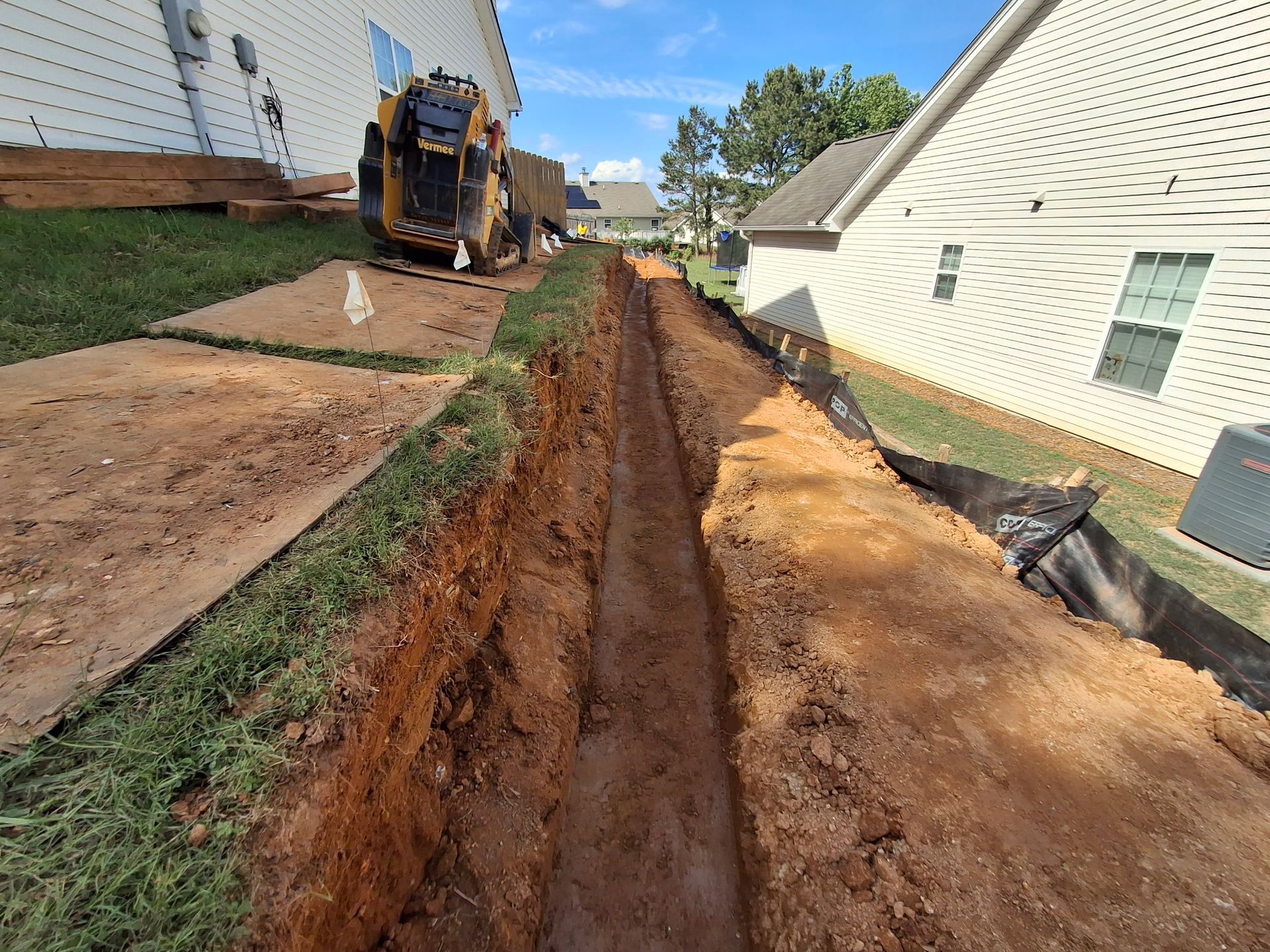A machine is digging a trench in front of a house.