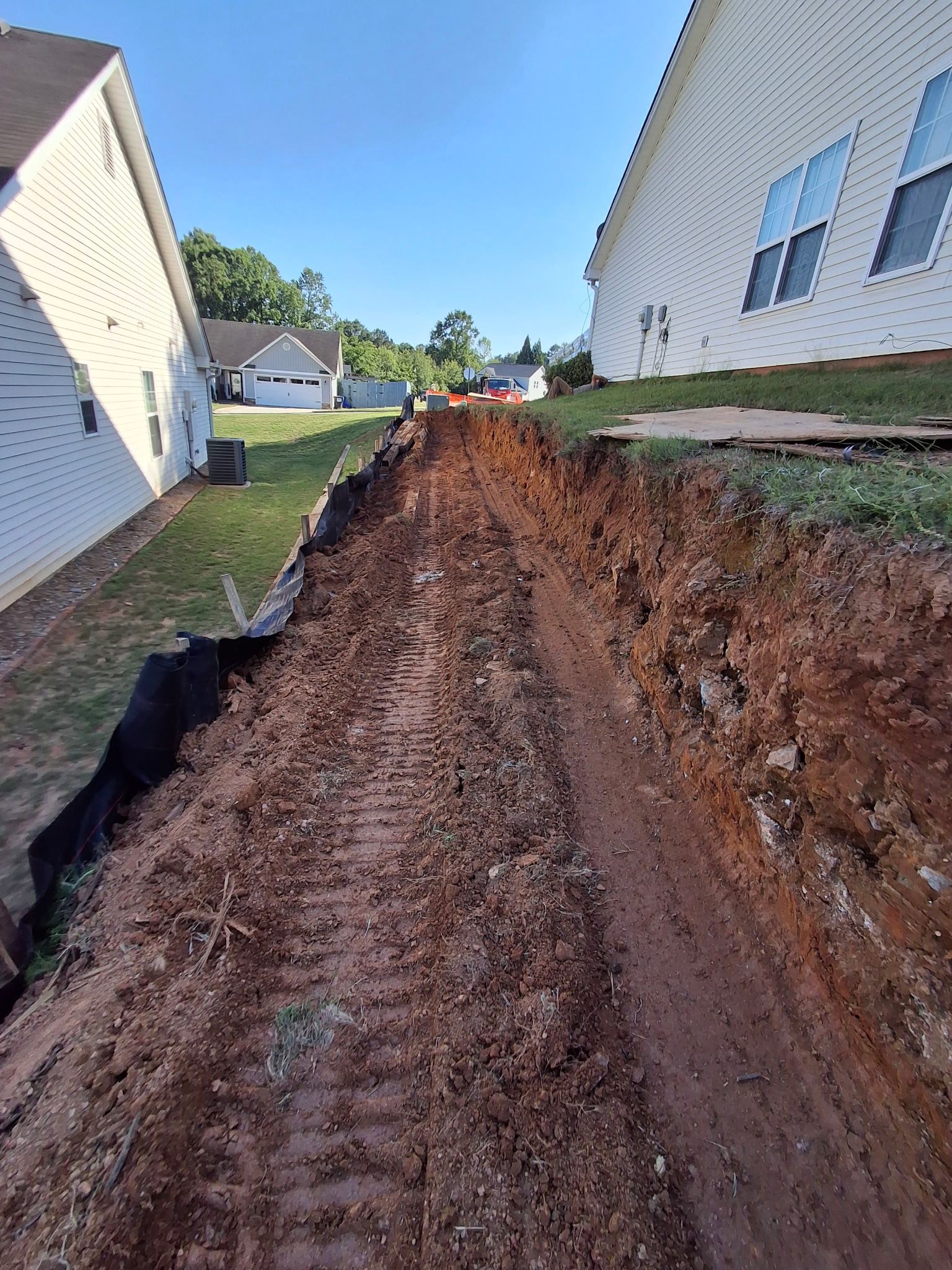 A dirt road between two houses in a residential area.