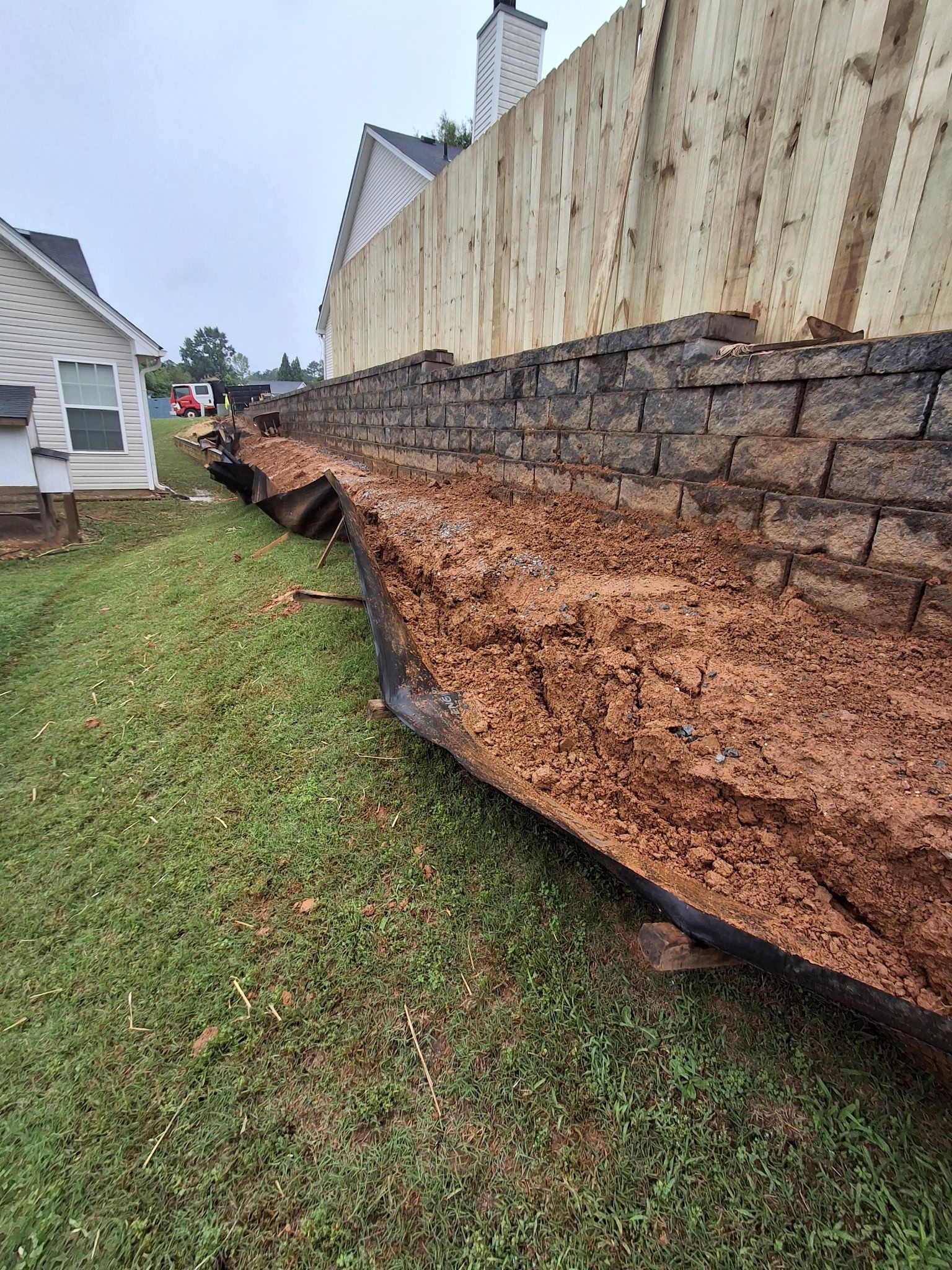 A brick wall is sitting on top of a lush green field next to a house.