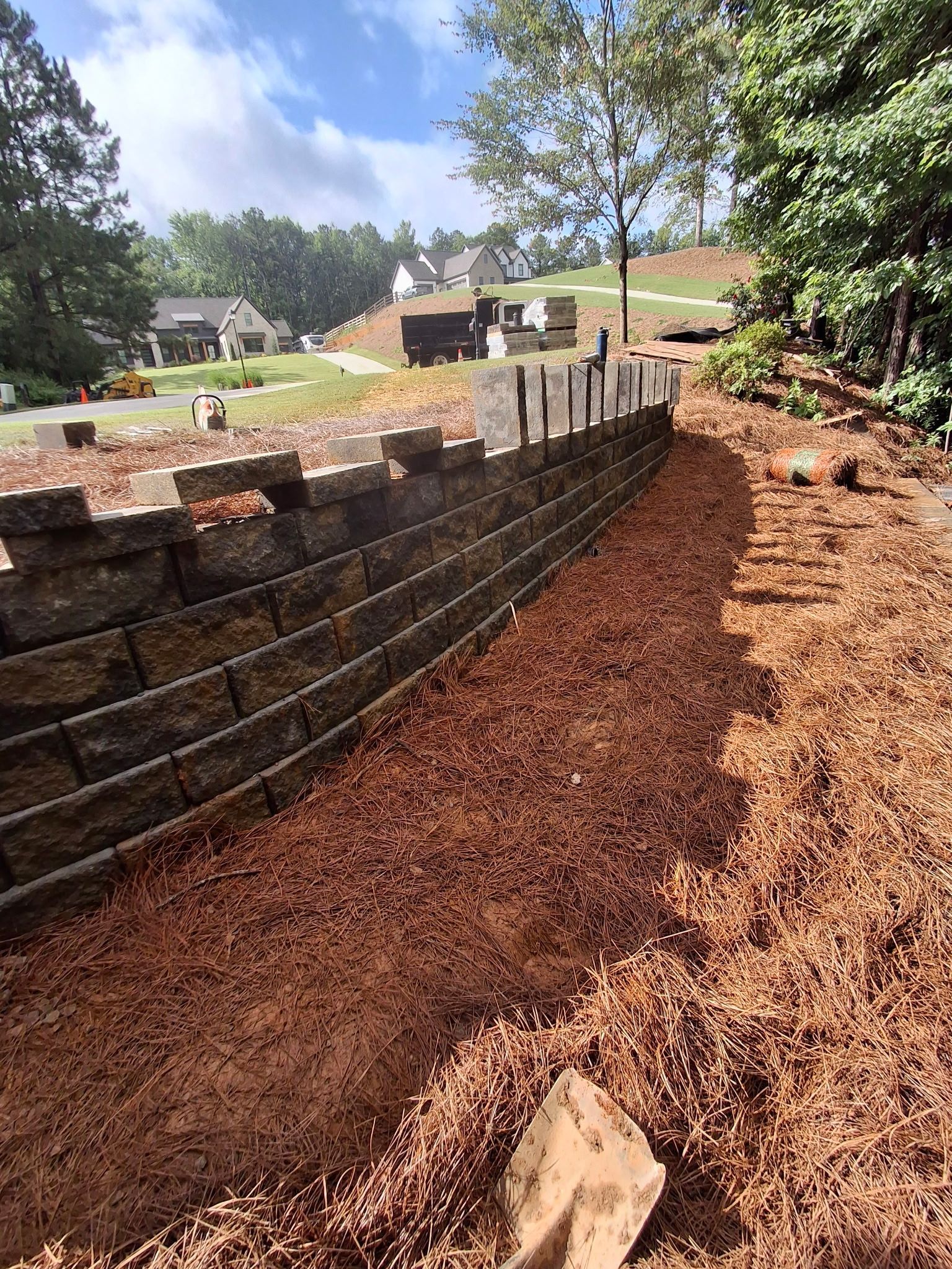 A brick wall is being built next to a pile of mulch.