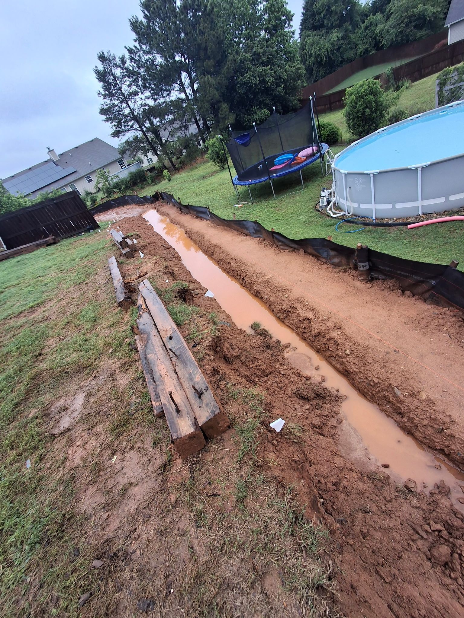 A muddy road leading to a pool in a backyard.