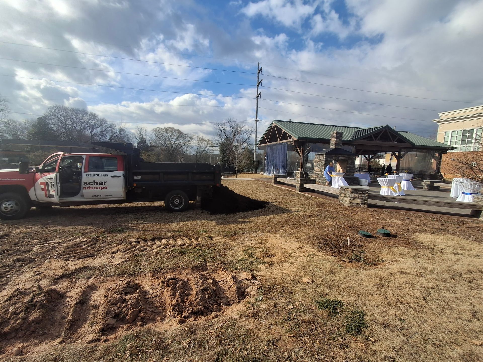 A dump truck is parked in a dirt field in front of a house.