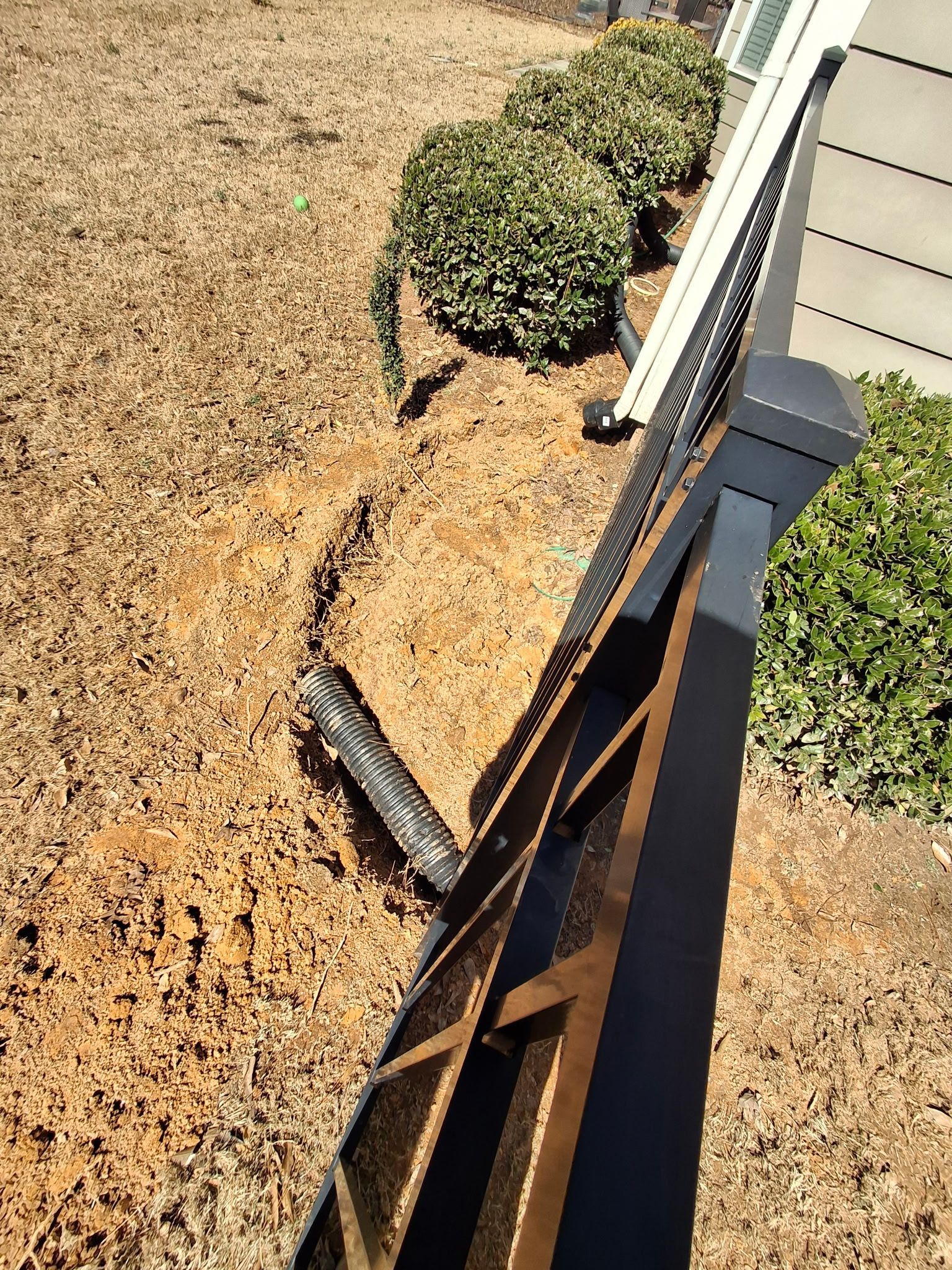 Drainage running under a fence pulling water away from the house