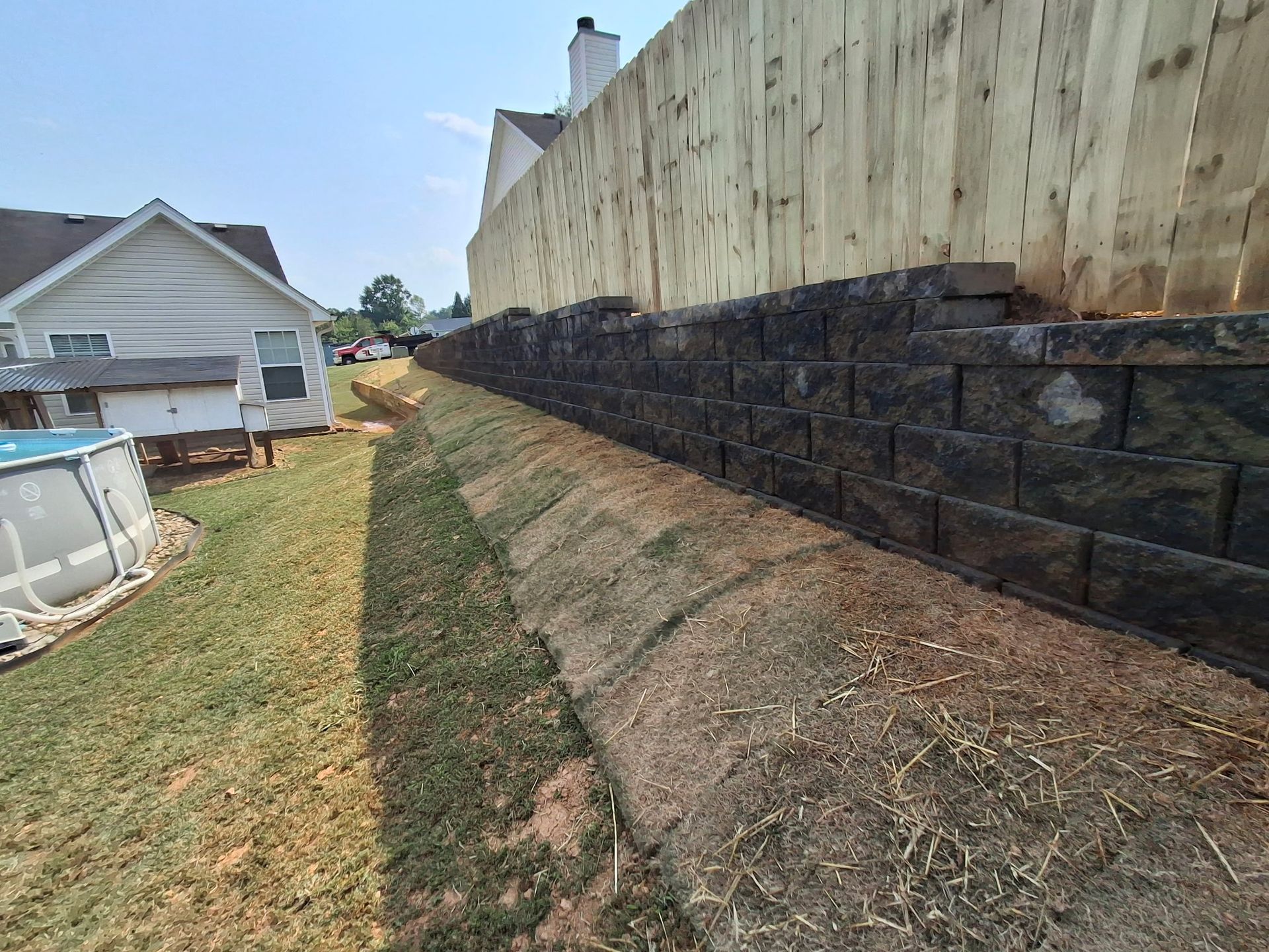 A house with a pool in the backyard next to a brick wall and a wooden fence.