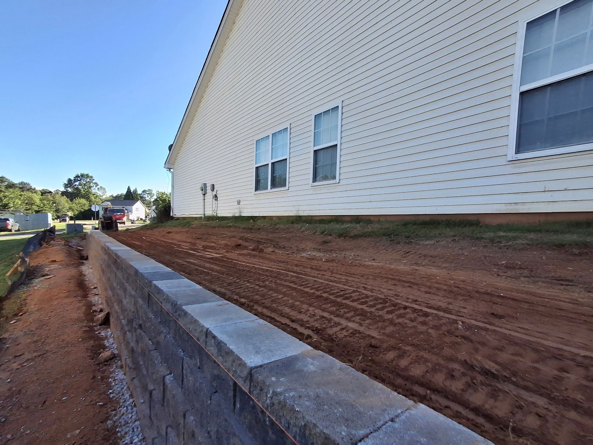 A white house with a brick wall in front of it.