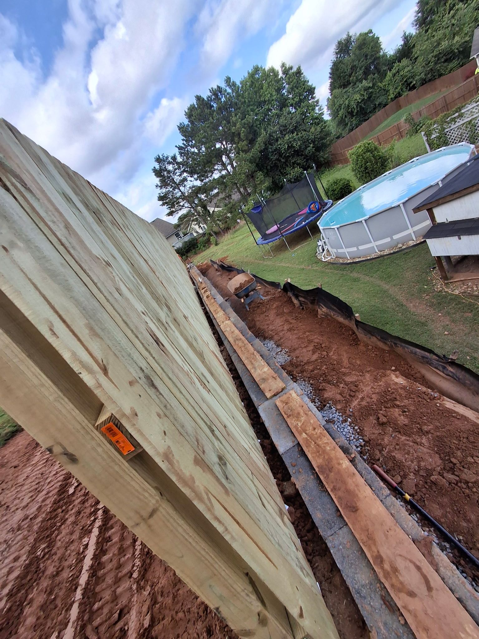 A wooden fence is being built next to a pool in a backyard.