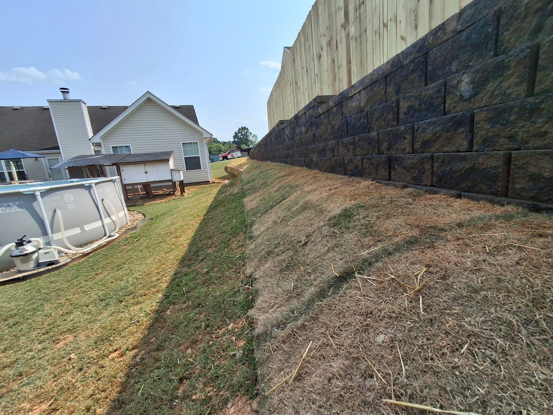 A house with a pool in the backyard next to a brick wall.
