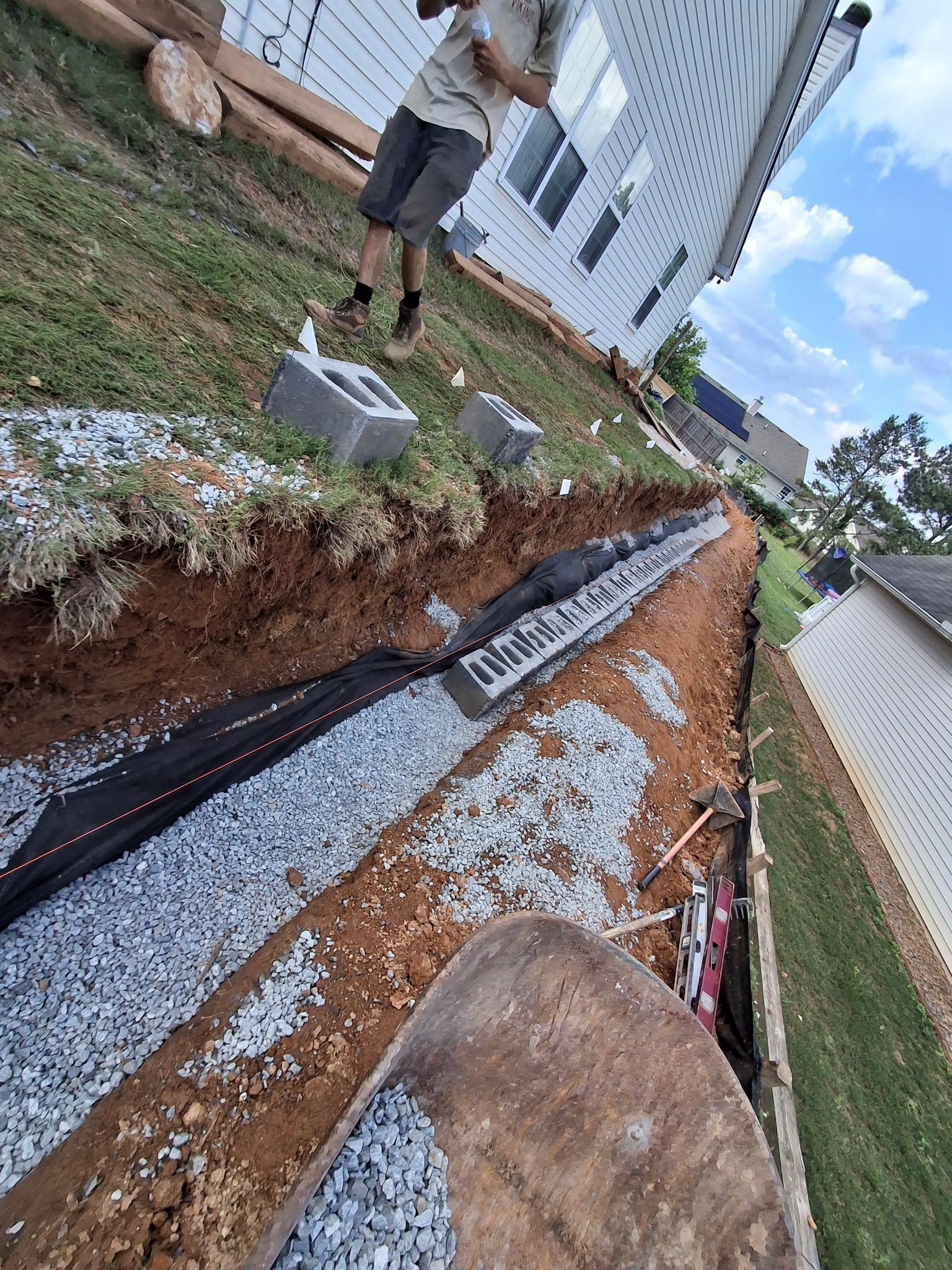 A man is standing in the dirt next to a house.