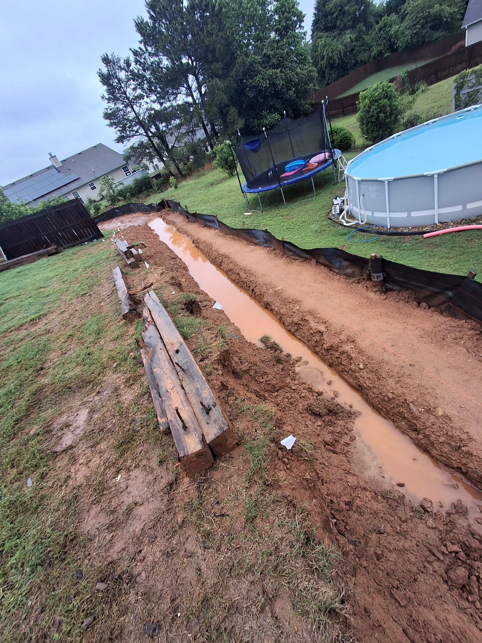 A muddy road leading to a pool in a backyard.